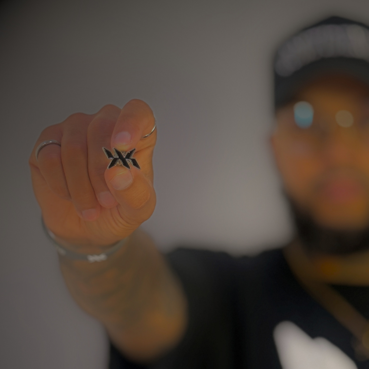 Hand holding the DNA Strand lapel pin in front of a blurred background, featuring the signature IAC Lyfestyle DNA logo.