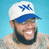 Smiling model wearing a blue and white DNA Strand snapback hat by IAC Lyfestyle.