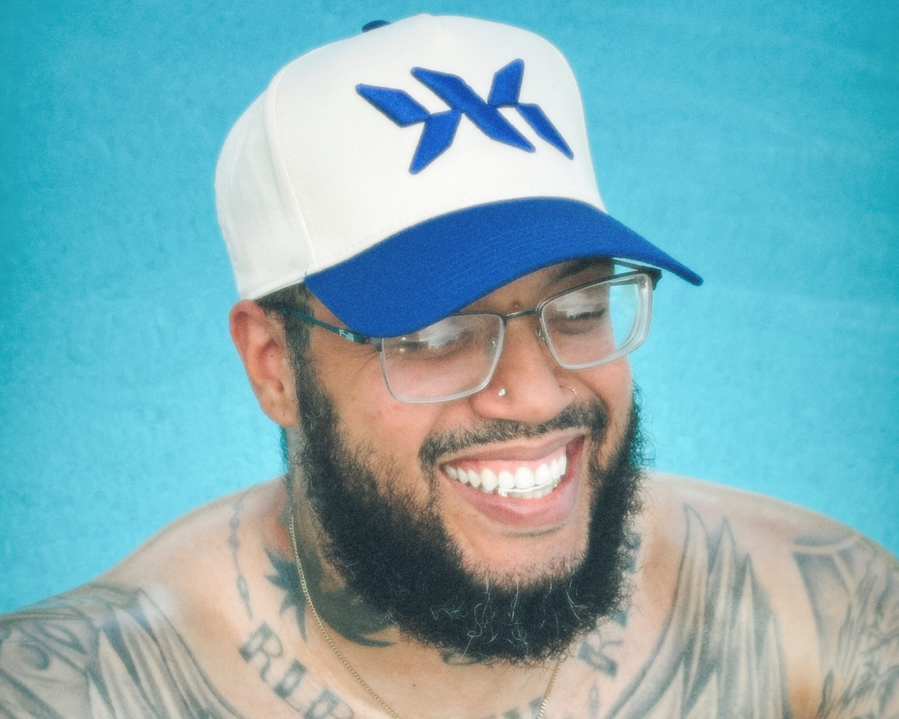 Smiling model wearing a blue and white DNA Strand snapback hat by IAC Lyfestyle.