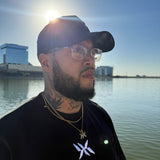 Model wearing IAC Essentials Kit featuring DNA Strand logo tee, snapback hat, and DNA pendant chain by water