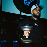 Man training in gym wearing IAC DNA Strand snapback, logo tee, and DNA pendant chain